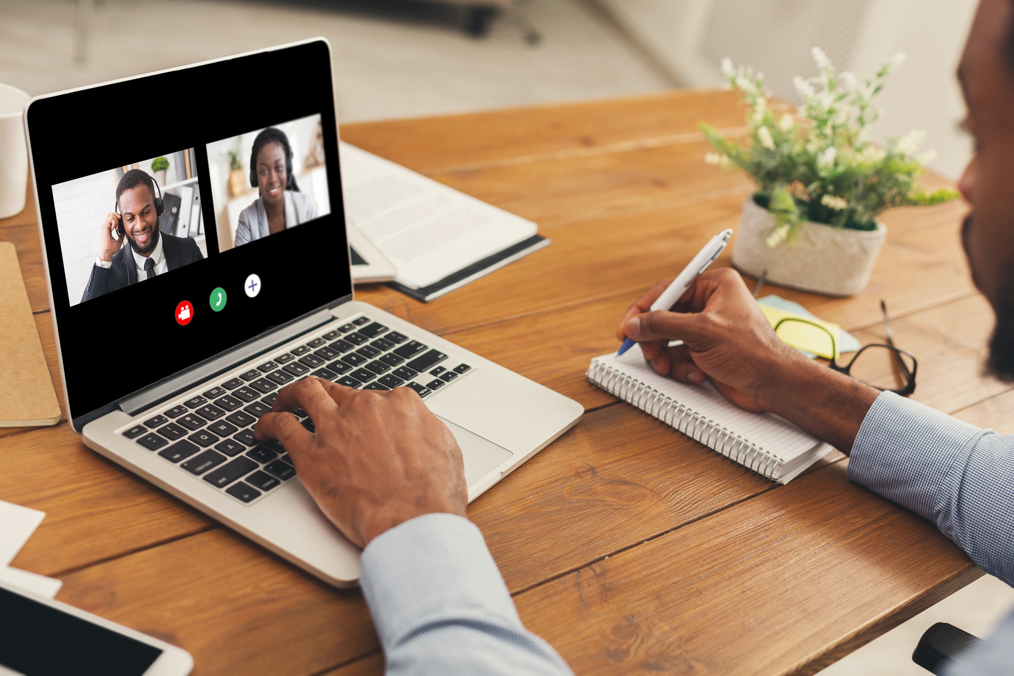 Unrecognizable black man watching business webinar at laptop and writing notes